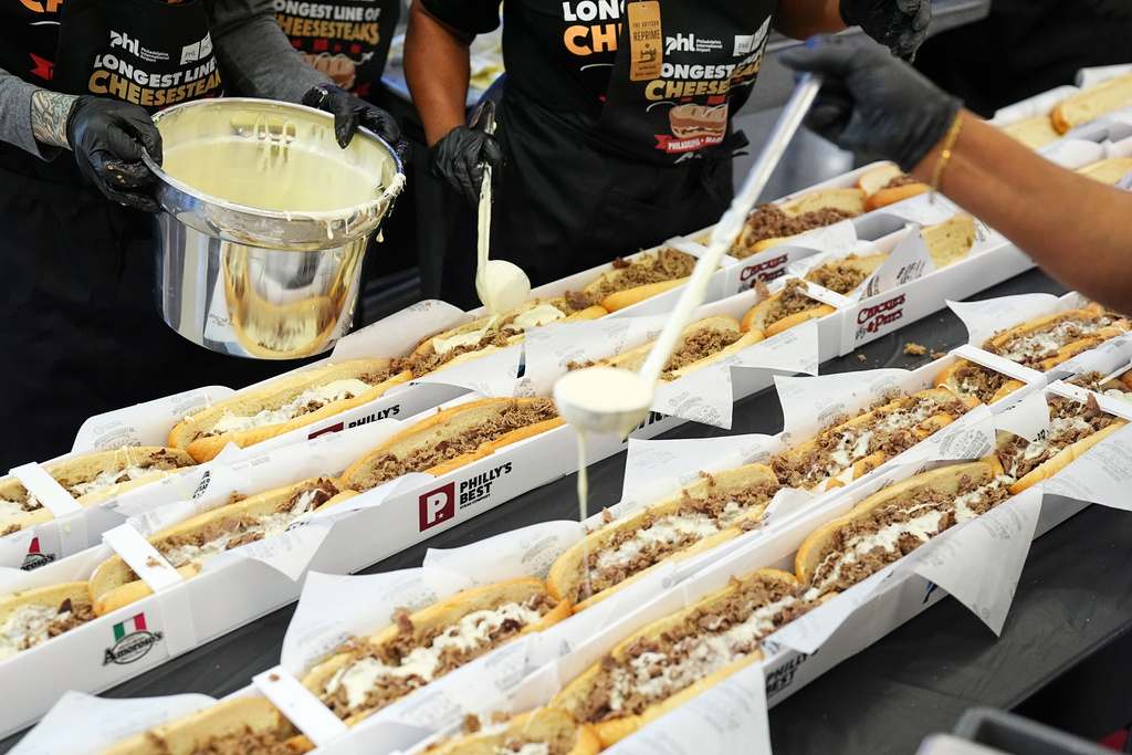 Volunteers assemble cheesesteaks in a Guinness World Record attempt on National Cheesesteak Day at Philadelphia International Airport, Tuesday, March 24, 2026, in Philadelphia. (AP Photo/Matt Rourke)