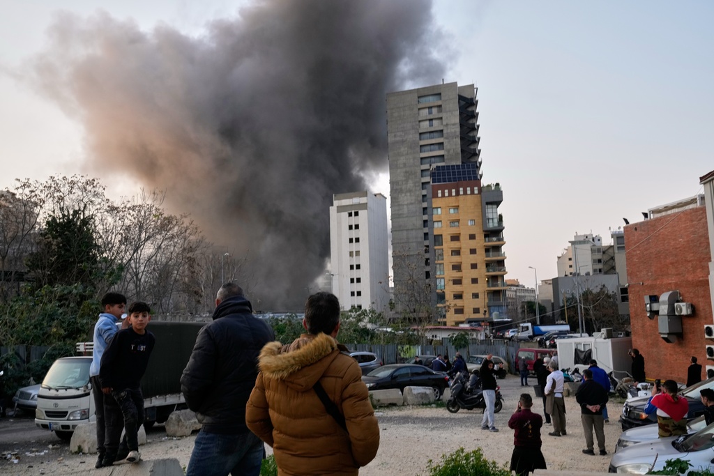 Residents watch as smoke rises from a nearby building during an Israeli strike in central Beirut, Lebanon, Thursday, March 12, 2026. (AP Photo/Hussein Malla)