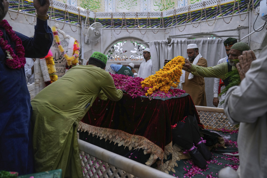 Devotees lay garland and ceremonial cloth locally called 'chaddar' on the shrine of mystic and scholar, Hazrat Ali Hajveri, popularly known as Data Ganj Bakhsh during celebrations of the three-day annual festival or 'Urs' at his shrine, in Lahore, Pakistan, Thursday, Aug. 14, 2025. (AP Photo/K.M. Chaudary)