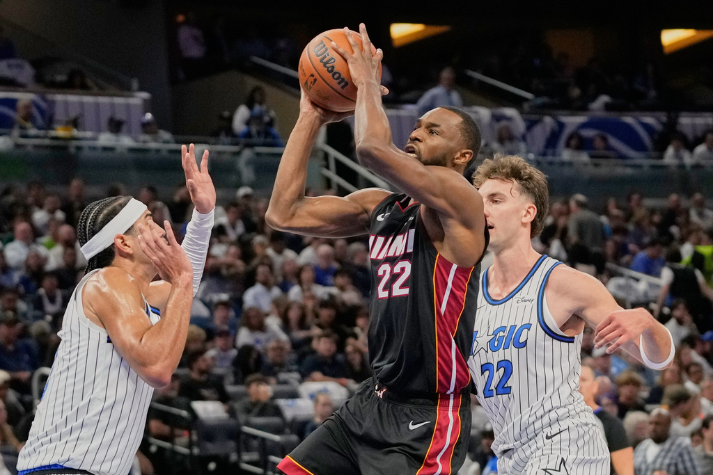 Miami Heat forward Andrew Wiggins, center, gets between Orlando Magic guard Anthony Black, left, and forward Franz Wagner, right, for a shot during the first half of an NBA basketball game, Wednesday, Oct. 22, 2025, in Orlando, Fla. (AP Photo/John Raoux)