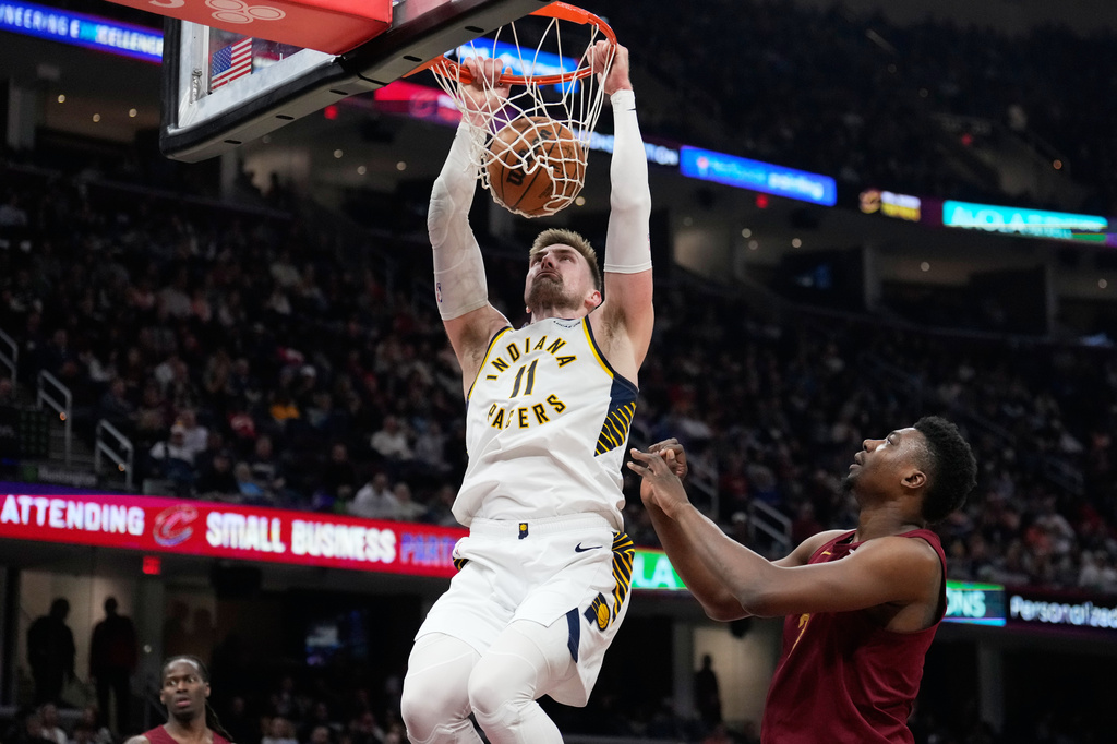 Indiana Pacers center Micah Potter (11) dunks next to Cleveland Cavaliers center Thomas Bryant, right, in the first half of an NBA basketball game in Cleveland, Sunday, April 5, 2026. (AP Photo/Sue Ogrocki)