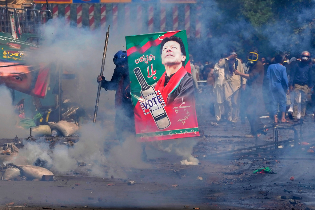 FILE - Supporters of former Prime Minister Imran Khan take cover after riot police officers fire tear gas to disperse them during clashes, in Lahore, Pakistan, Wednesday, March 15, 2023. (AP Photo/K.M. Chaudary, File)
