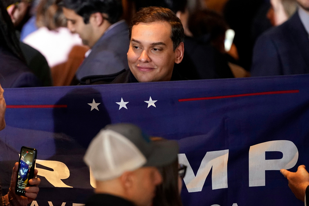 FILE - Former Rep George Santos, R-N.Y., holds a sign before Republican presidential candidate former President Donald Trump speaks at a primary election night party in Nashua, N.H., Jan. 23, 2024. (AP Photo/Pablo Martinez Monsivais, file)