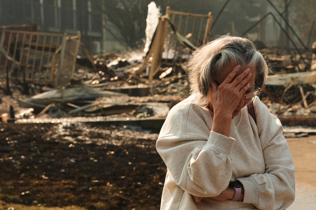 Miriam Sim, 76, reacts while talking about her neighborhood largely burning to the ground after a wildfire hit the northern part of Spokane, Wash., Monday, Aug. 3, 2026. (AP Photo/Lindsey Wasson)