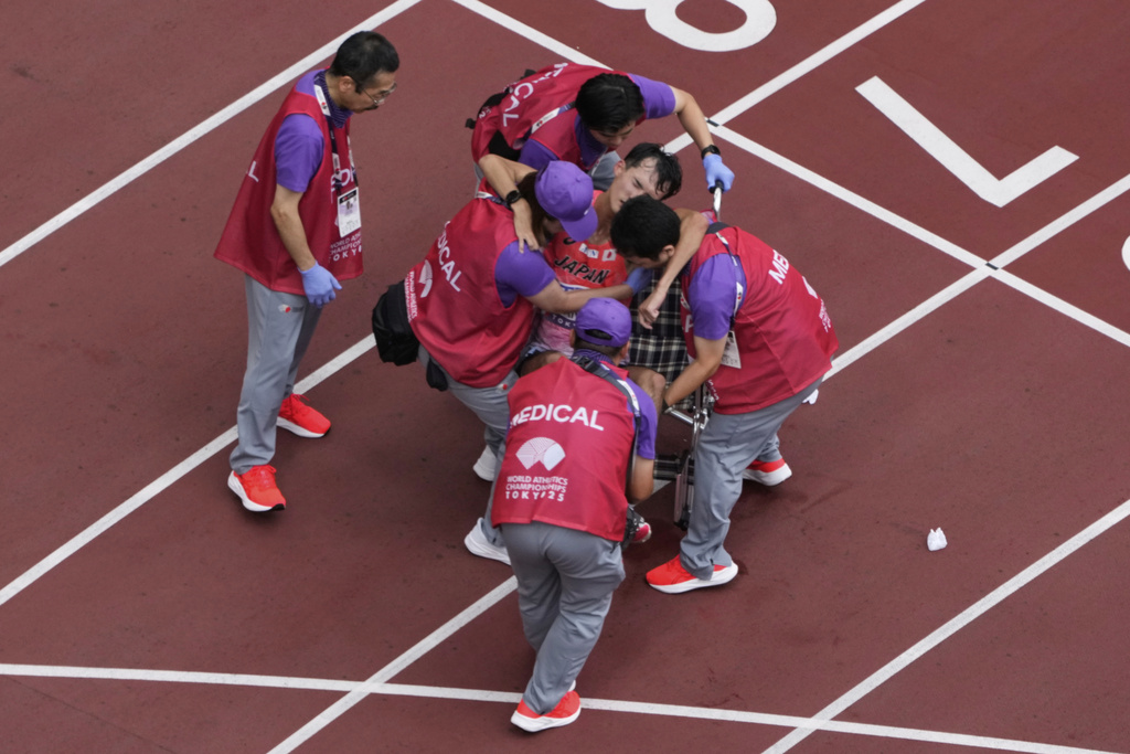 Japan's Masatora Kawano is assisted by medial team after crossing the finish line of the men's 35 kilometers race walk at the World Athletics Championships in Tokyo, Saturday, Sept. 13, 2025. (AP Photo/Bernat Armangue)