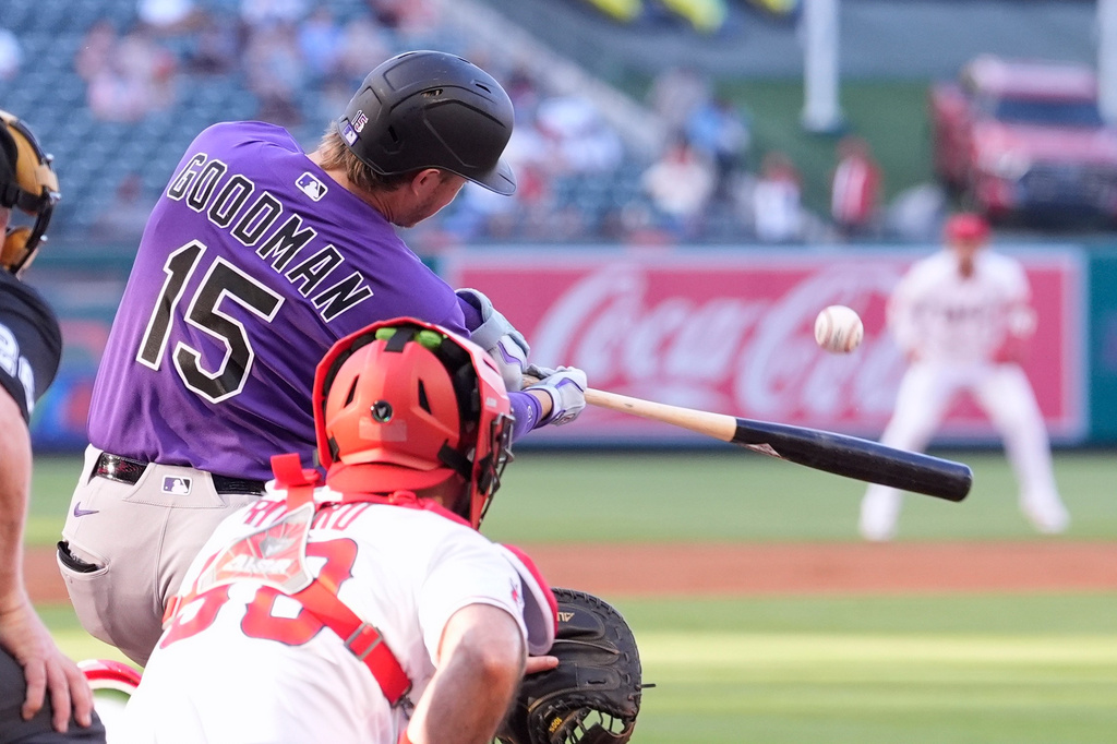 Colorado Rockies' Hunter Goodman, left, hits a solo home run as Los Angeles Angels catcher Sebastián Rivero watches during the second inning of a baseball game Tuesday, June 2, 2026, in Anaheim, Calif. (AP Photo/Mark J. Terrill)