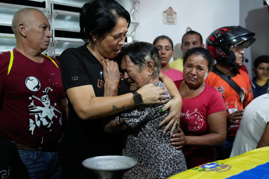 Emelyn Torres and Maria Cristina Fernandez, the sister and grandmother of Edilson Torres, a Venezuelan police officer who died in prison after being detained on accusations of treason, embrace during his wake at his home in Guanare, Venezuela, Monday, Jan. 12, 2026. (AP Photo/Ariana Cubillos)