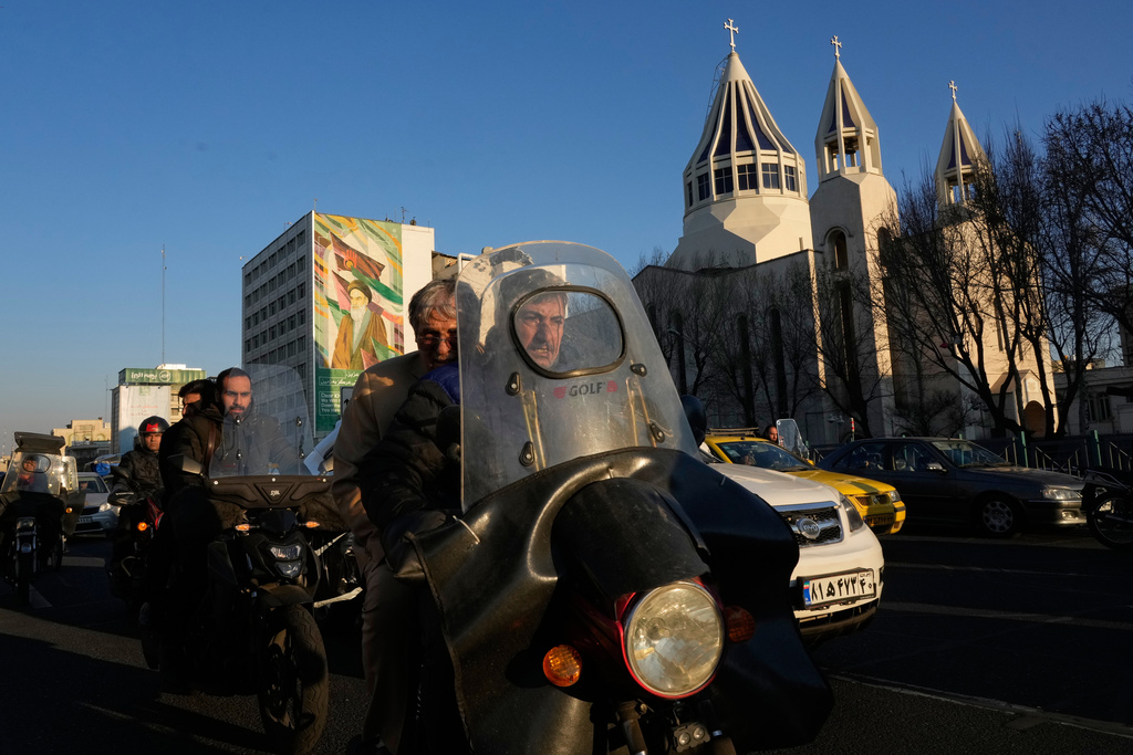 Commuters drive past Saint Sarkis church and a mural of the late Iranian revolutionary founder Ayatollah Khomeini in downtown Tehran, Iran, Wednesday, Feb. 25, 2026. (AP Photo/Vahid Salemi)