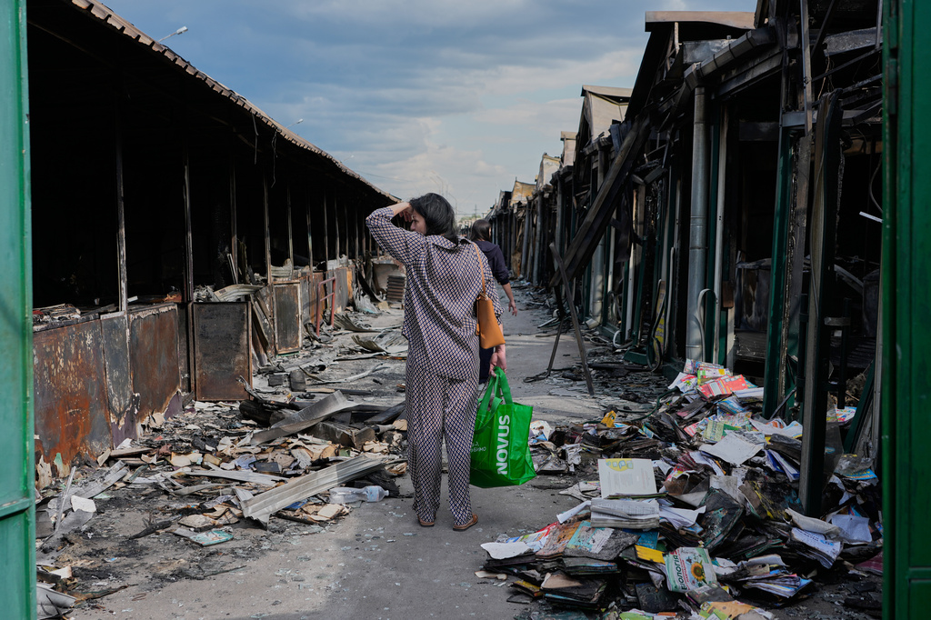 A woman reacts as she looks at charred books after a fire at the country's biggest book market, caused by a recent Russian missile attack, in Kyiv, Ukraine, Wednesday, Aug. 19, 2026. (AP Photo/Efrem Lukatsky)