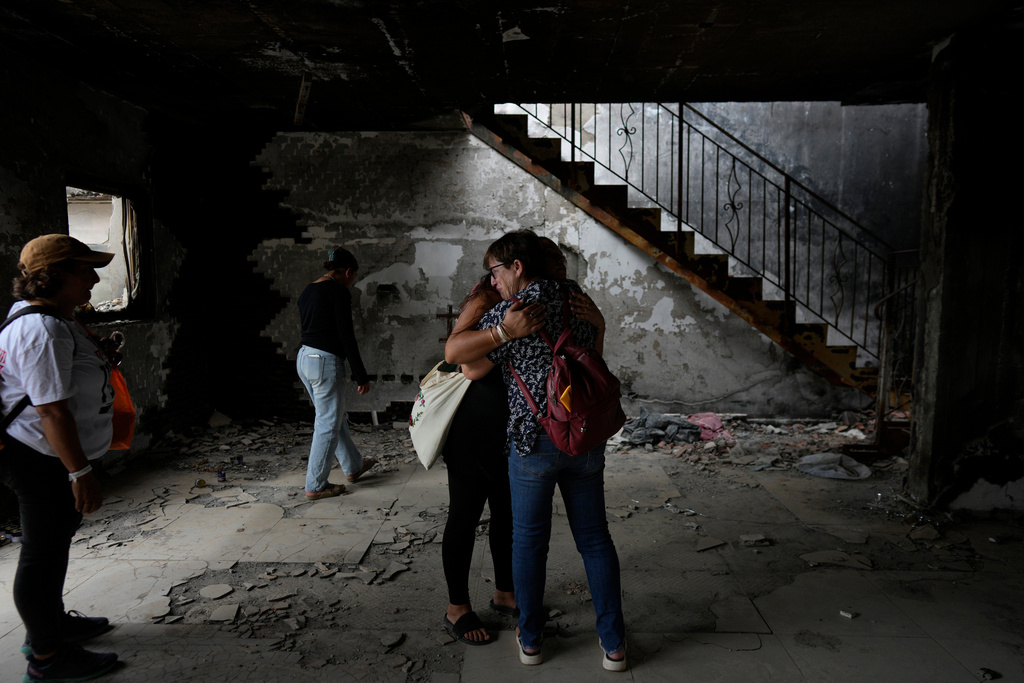 Israelis embrace each other at the house of Maayan and Yuval Bar killed by Hamas, as Israel marks the one-year anniversary of the Hamas attack on Israel, at the Kibbutz Be'eri, an Israeli communal farm on the Gaza border, on Monday, Oct. 7, 2024. (AP Photo/Ohad Zwigenberg)