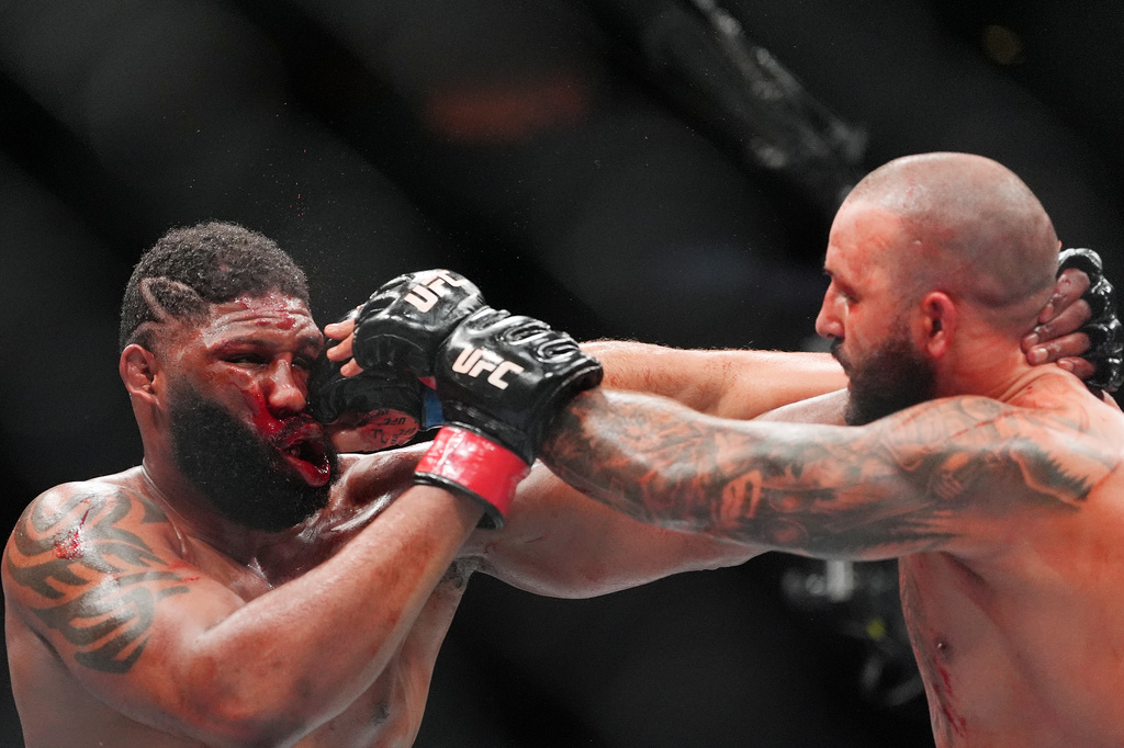 Curtis Blaydes, left, of the United States, absorbs a punch from Josh Hokit, of the United States, in a heavyweight bout at a UFC 327 mixed martial arts event, Saturday, April 11, 2026, in Miami. (AP Photo/Rebecca Blackwell)