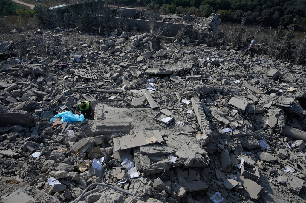 A rescue worker, left, searches for victims under the rubble of a home that was hit by an Israeli airstrike in Ansar village, southern Lebanon, Saturday, Aug. 15, 2026. (AP Photo/Mohammed Zaatari)