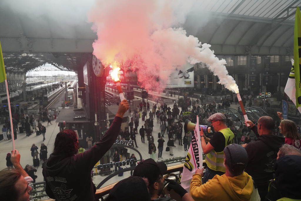 Railway workers hold smoke bombs in the Gare de Lyon train station, during the « Bloquons Tout » (Block Everything) protest movement in Paris, France, Wednesday, Sept. 10, 2025. (AP Photo/Thibault Camus)