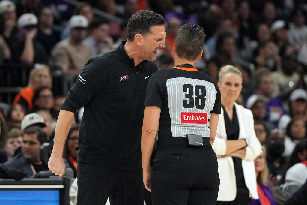 Phoenix Mercury head coach Nate Tibbetts, left, yells at official Lamont Simpson (38) after a foul during the second half of Game 4 of the WNBA basketball finals against the Las Vegas Aces, Friday, Oct. 10, 2025, in Phoenix. (AP Photo/Rick Scuteri)