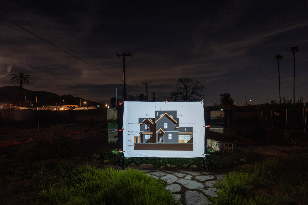 A design of Angela and Pete Mitchell's new home, as it will look after it is rebuilt, is projected on a screen on the property where their home destroyed in the Eaton Fire once stood, in Altadena, Calif., Thursday, Dec. 4, 2025. (AP Photo/Jae C. Hong)