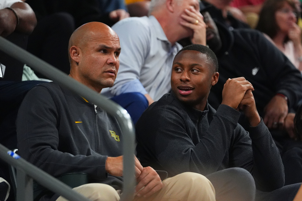 NCAA college football quarterback DJ Lagway, right, talks with Baylor head football coach Dave Aranda during the first half of an NCAA college basketball game between Baylor and Iowa State Wednesday, Jan. 7, 2026, in Waco, Texas. (AP Photo/Julio Cortez)