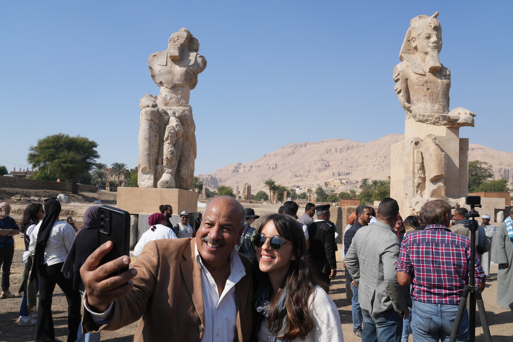 Visitors take photos with the two giant reassembled alabaster statues of Pharoah Amenhotep III, in the southern city of Luxor, Egypt, Sunday, Dec. 14, 2025. (AP Photo/Amr Nabil)