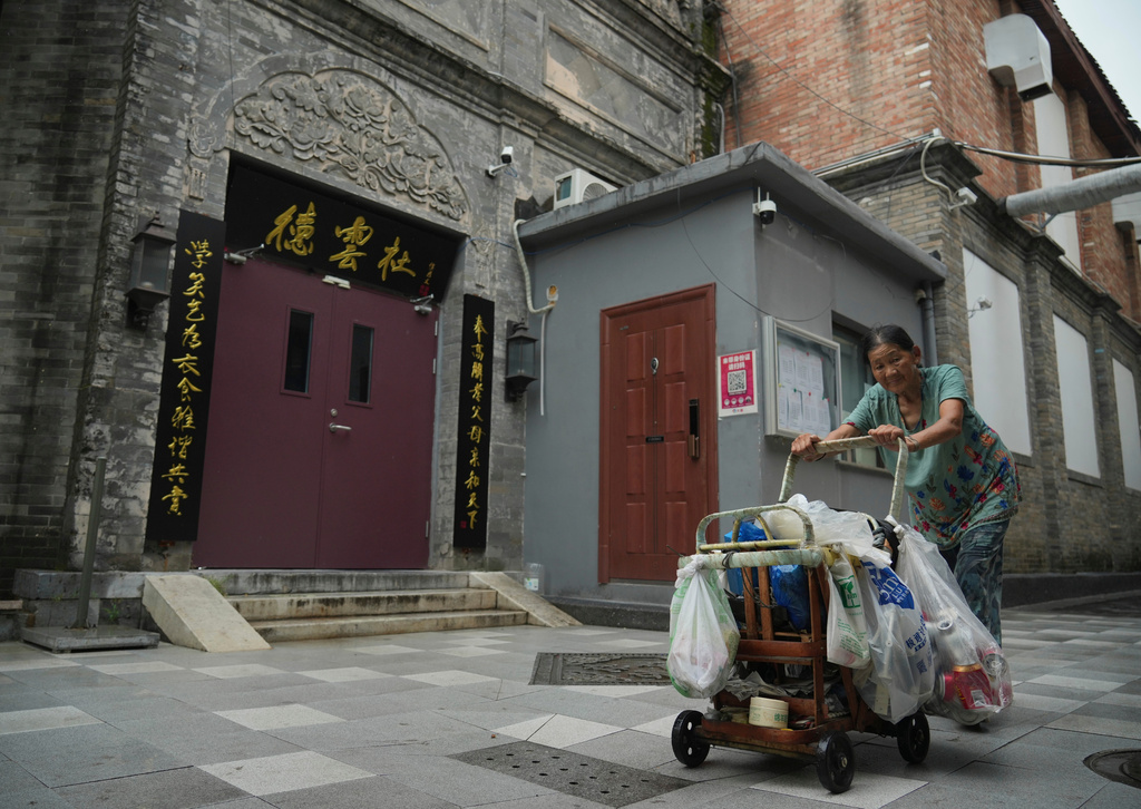 A woman pushes a cart past a Deyunshe theater, part of the comedy group founded by Guo Degang, in Beijing, Saturday, Aug. 22, 2026. (AP Photo/Achmad Ibrahim)