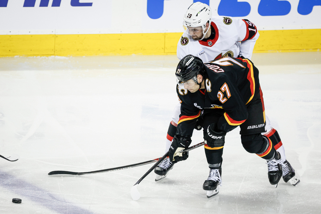 Ottawa Senators' Drake Batherson, top, is checked by Calgary Flames' Matt Coronato during the second period of an NHL hockey game in Calgary on Thursday, March 5, 2026. (Jeff McIntosh/The Canadian Press via AP)
