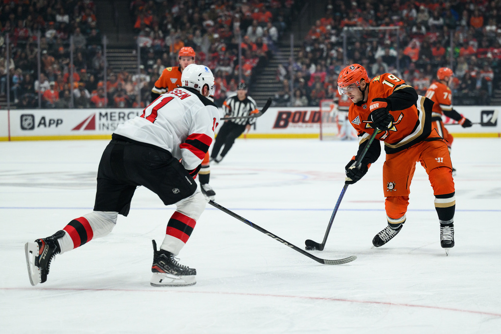 Anaheim Ducks right wing Troy Terry (19) looks to shoot while under pressure from New Jersey Devils right wing Stefan Noesen, left, during the first period of an NHL hockey game Sunday, Nov. 2, 2025, in Anaheim, Calif. (AP Photo/William Liang)
