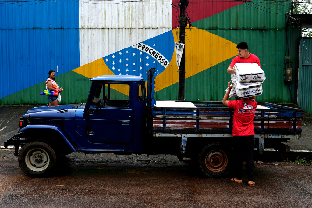 Workers load a vehicle with supplies in front of a wall with an image of the French and Brazilian flags, representing the commercial relationship established along the Oiapoque River between French Guiana and the city of Oiapoque, Amapa state, Brazil, Wednesday, March 11, 2026. (AP Photo/Eraldo Peres)