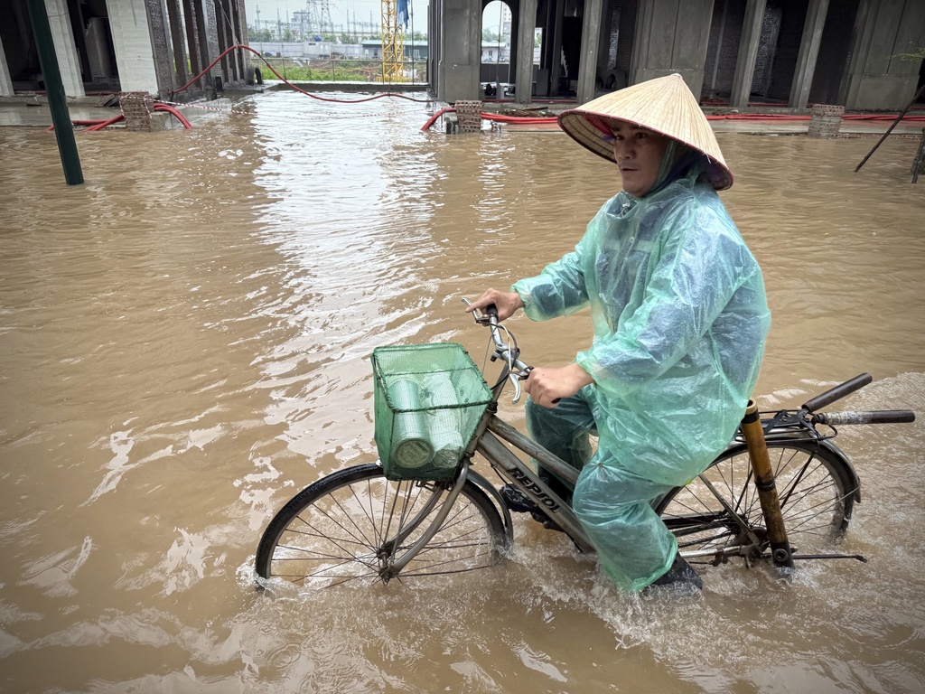 A man rides a bicycle on a flooded street caused by Typhoon Kajiki in Hanoi, Vietnam, Wednesday, Aug. 27, 2025. (AP Photo/Hau Dinh)