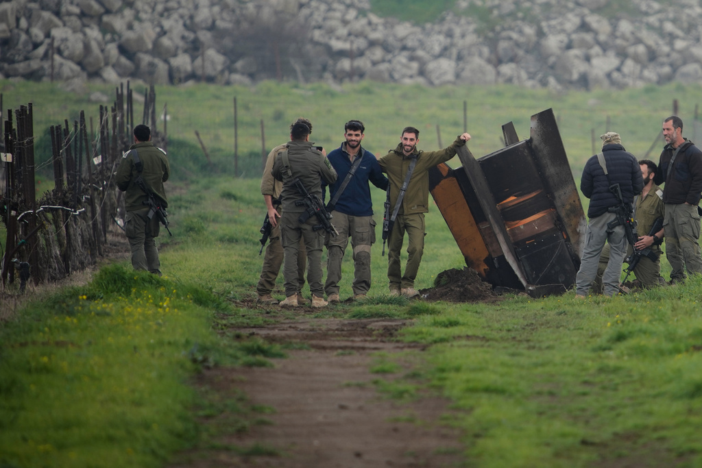 Israeli soldiers take photographs next to a fragment of a missile fired from Iran, and intercepted by Israeli defense system, embedded in an open field in the Israeli-controlled Golan Heights, Thursday, March 19, 2026. (AP Photo/Ohad Zwigenberg)