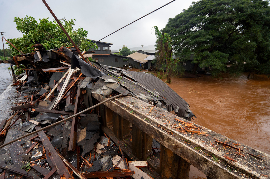 Debris from a storm-damaged house sits against a bridge along Kaukonahua Stream, caused by flooding from severe rains in Waialua, Hawaii, Friday, March 20, 2026. (AP Photo/Mengshin Lin)