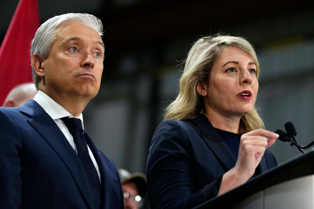 Canada Minister of Industry Melanie Joly speaks as Minister of Finance and National Revenue Francois-Philippe Champagne looks on at a news conference on Canada's response to U.S. tariffs, at a roofing company in Ottawa, on Tuesday, Aug. 25, 2026. (Justin Tang/The Canadian Press via AP)