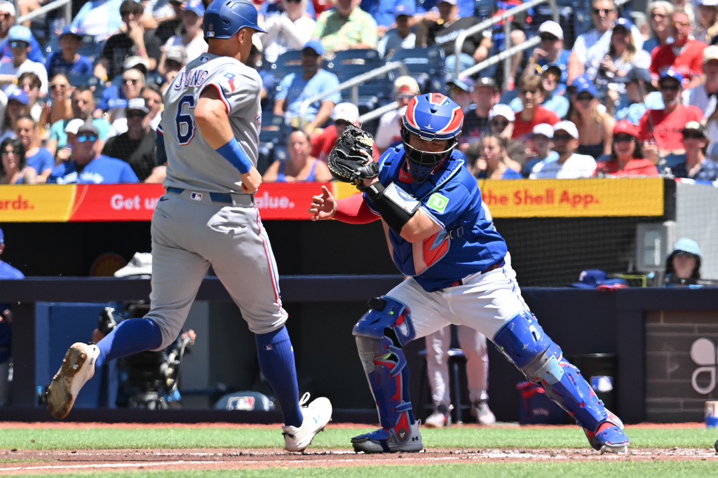 Toronto Blue Jays catcher Alejandro Kirk, righ, forces out Texas Rangers' Josh Jung (6) at the plate on a bases- loaded single during the first inning of a baseball game in Toronto, Sunday, June 28, 2026. (Jon Blacker/The Canadian Press via AP)