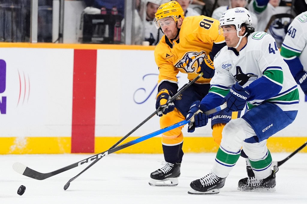 Nashville Predators center Jonathan Marchessault (81) and Vancouver Canucks left wing Kiefer Sherwood (44) vie for the puck during the second period of an NHL hockey game Monday, Nov. 3, 2025, in Nashville, Tenn. (AP Photo/George Walker IV)
