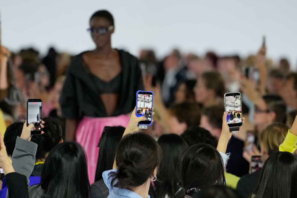 People take photos during the Prada women's Spring-Summer 2027 collection fashion show in Milan, Italy, Tuesday, Sept. 22, 2026. (AP Photo/Luca Bruno).