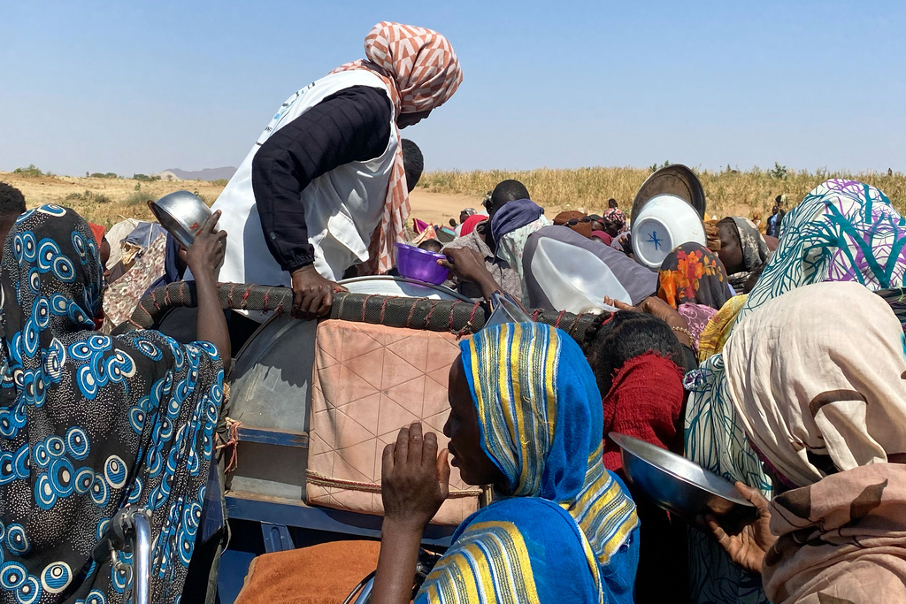 Sudanese who fled el-Fasher city, after Sudan's paramilitary forces killed hundreds of people in the western Darfur region, crowd to receive food at their camp in Tawila, Sudan, Sunday, Nov. 2, 2025. (AP Photo/Mohammed Abaker)