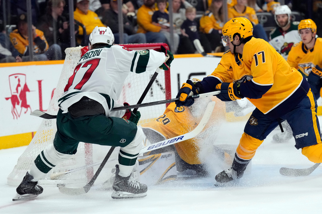 Nashville Predators right wing Luke Evangelista (77) keeps Minnesota Wild left wing Kirill Kaprizov (97) away from the net during the first period of an NHL hockey game Saturday, April 11, 2026, in Nashville, Tenn. (AP Photo/Mark Humphrey)