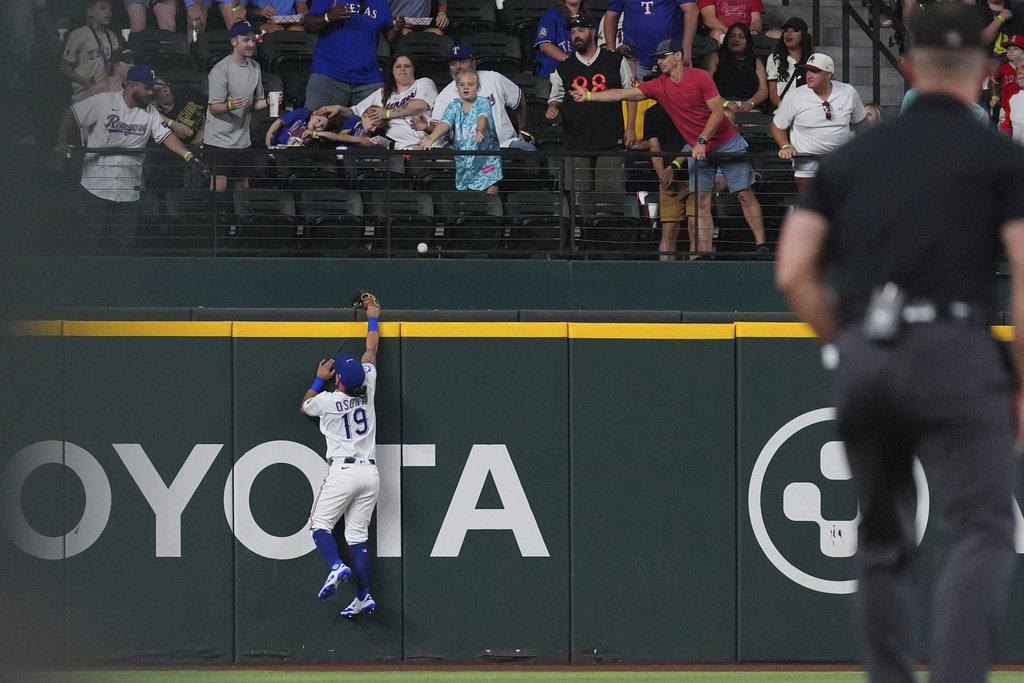 Texas Rangers outfielder Alejandro Osuna (19) cannot reach a home run hit by Los Angeles Angels' Zach Neto during the first inning, Monday, Aug. 25, 2025, in Arlington, Texas. (AP Photo/LM Otero)