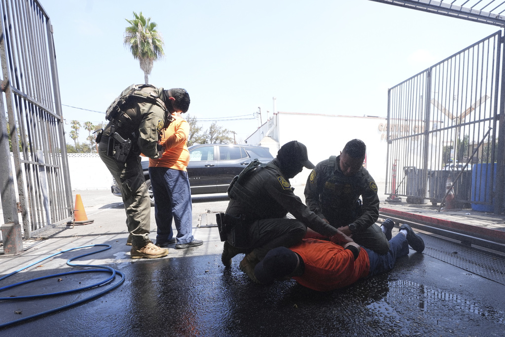 Immigration agents detain two men at a car wash on Friday, Aug. 15, 2025, in Montebello, Calif. (AP Photo/Gregory Bull)