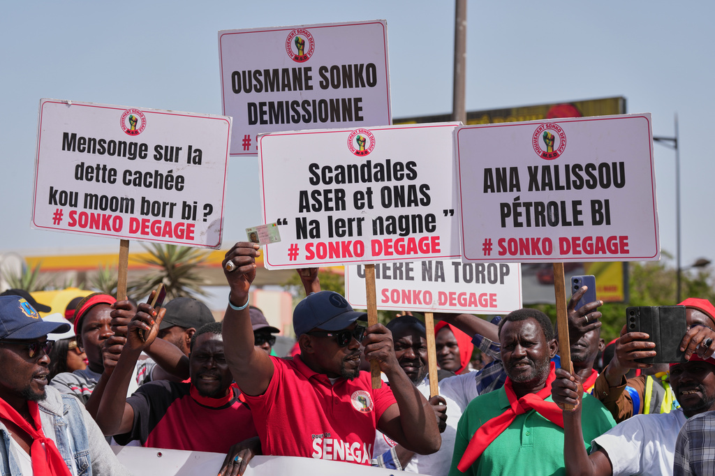 Workers hold placards as they march to demand that the government honor its commitments and address their concerns, in Dakar, Senegal, Wednesday, April 8, 2026. (AP Photo/Misper Apawu)