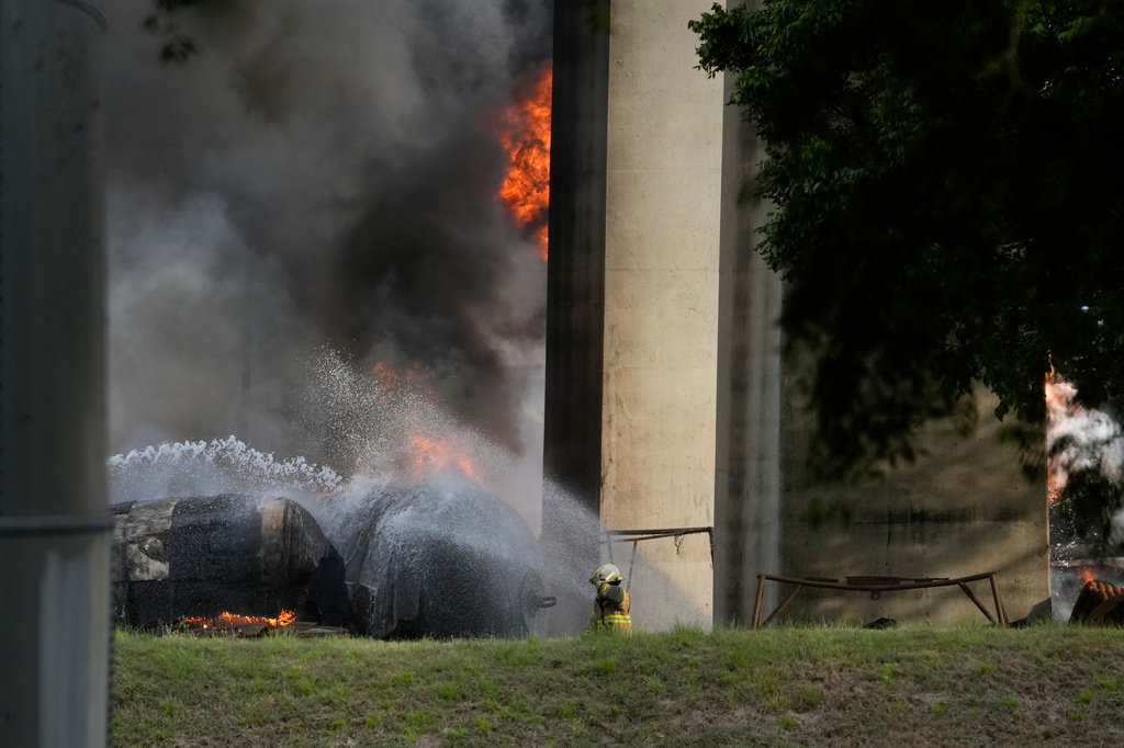A firefighter sprays water on gas trucks that caught fire after several exploded under Las Americas Bridge next to the Panama Canal in Panama City, Panama, Monday, April 6, 2026. (AP Photo/Matias Delacroix)