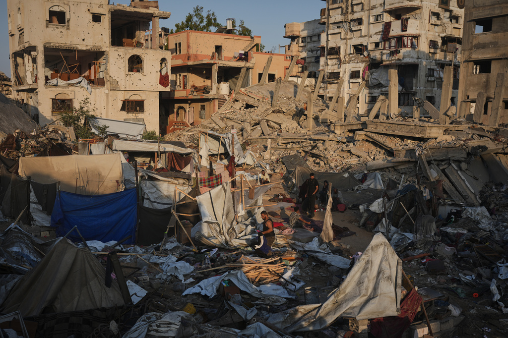 Palestinians salvage their belongings from the rubble of a building and tents destroyed in an Israeli airstrike in Gaza City, Thursday, July 30, 2026. (AP Photo/Jehad Alshrafi)