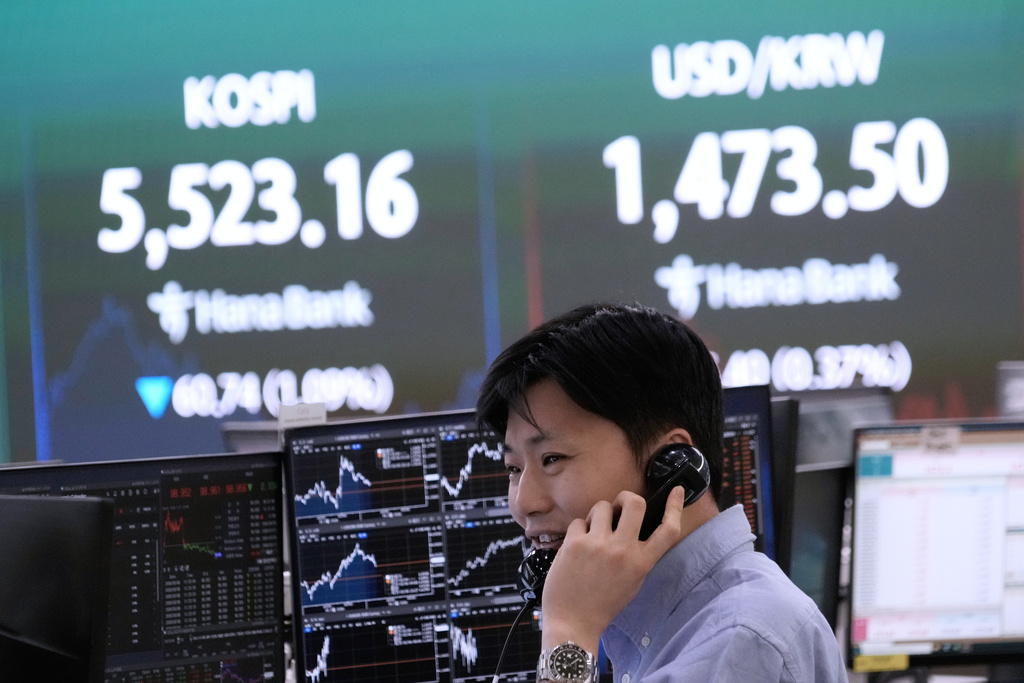 A currency trader talks on the phone near a screen showing the Korea Composite Stock Price Index (KOSPI), top left, and the foreign exchange rate between U.S. dollar and South Korean won at the foreign exchange dealing room of the Hana Bank headquarters in Seoul, South Korea, Friday, March 6, 2026. (AP Photo/Ahn Young-joon)