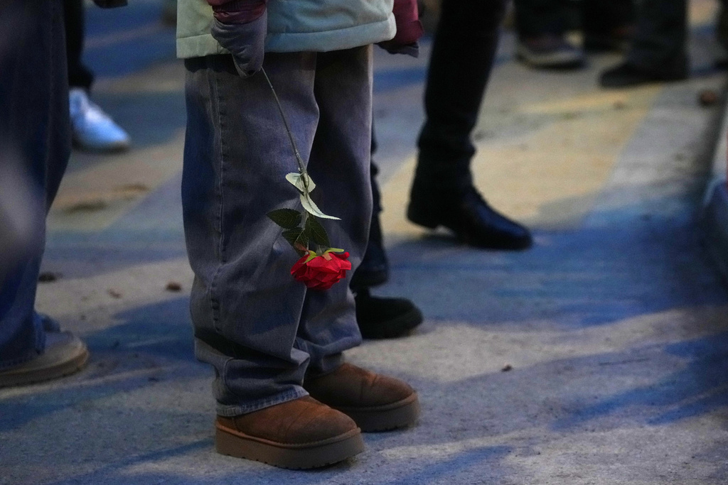 People bring flowers near the sealed off Le Constellation bar in Crans-Montana, Swiss Alps, Switzerland, Friday, Jan. 2, 2026, where a devastating fire left dead and injured during the New Year's celebrations. (AP Photo/ Antonio Calanni)