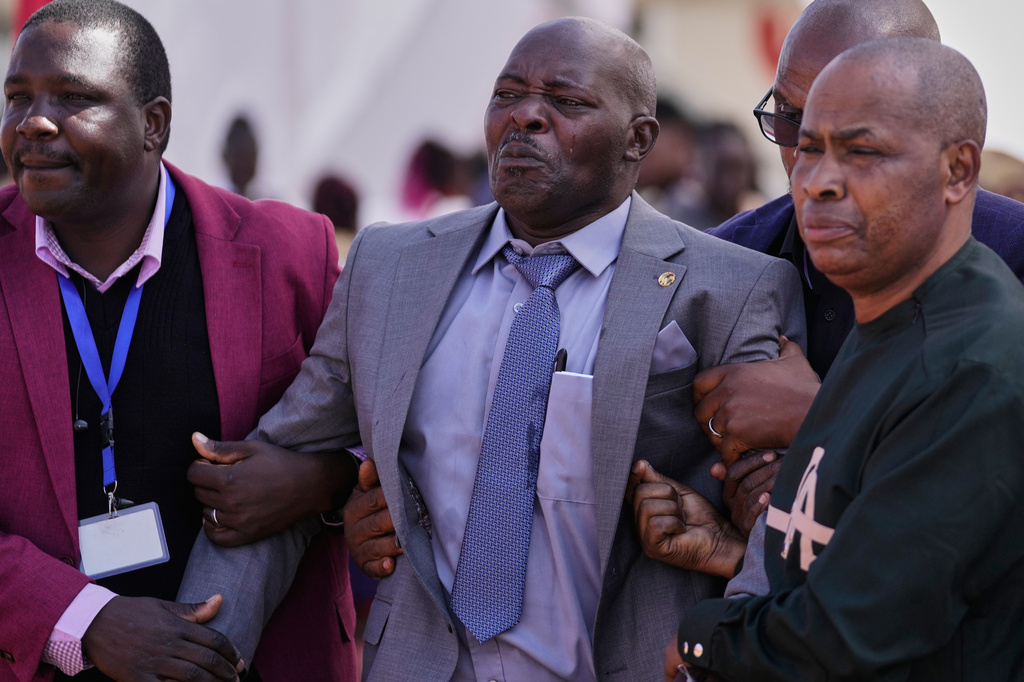 A father grieves beside the casket carrying the remains of his daughter, one of the 16 girls who died in the Utumishi Academy school fire, during a memorial service at Gilgil Stadium, Nakuru County, Kenya, Friday, June 12, 2026. (AP Photo/Brian Inganga)