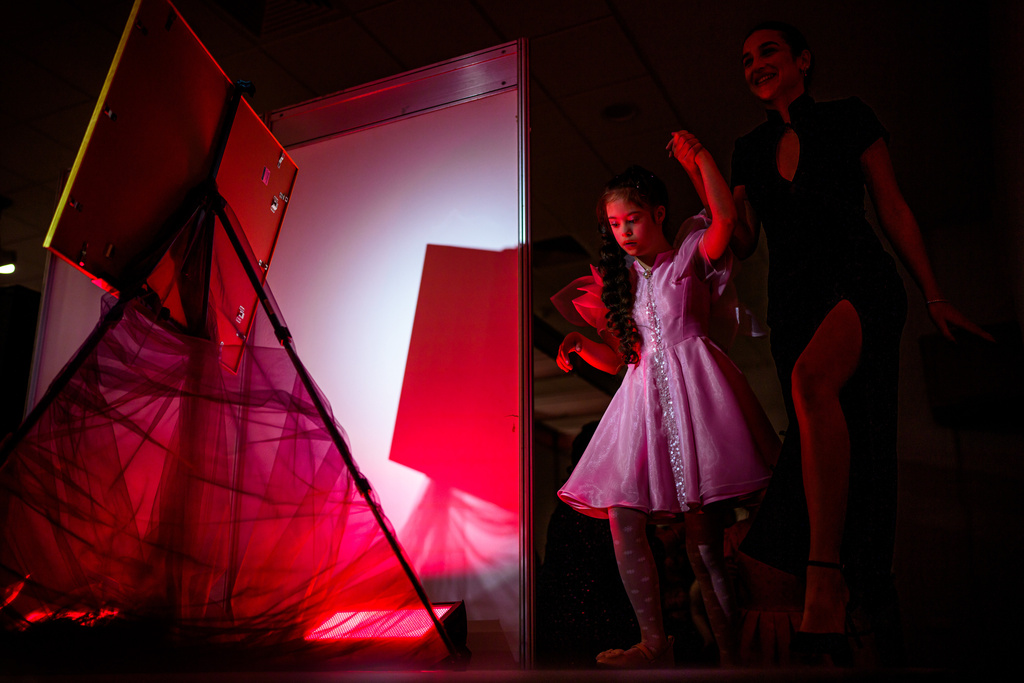 Luiza Coranga, right, assists her sister Maria onto the catwalk during the SEEN Anonymous Seamstresses Gala, an event organised by the Down Plus Bucharest, an NGO supporting youngsters with Down Syndrome and other intellectual disabilities, in Bucharest, Romania, Wednesday, March 18, 2026, ahead of the World Down Syndrome Day, on March 21. (AP Photo/Andreea Alexandru)