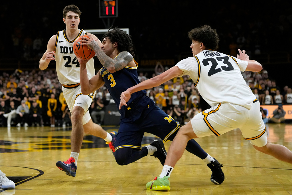 Michigan guard Elliot Cadeau (3) drives to the basket between Iowa guard Tate Sage (24) and guard Isaia Howard (23) during the first half of an NCAA college basketball game, Thursday, March 5, 2026, in Iowa City, Iowa. (AP Photo/Charlie Neibergall)