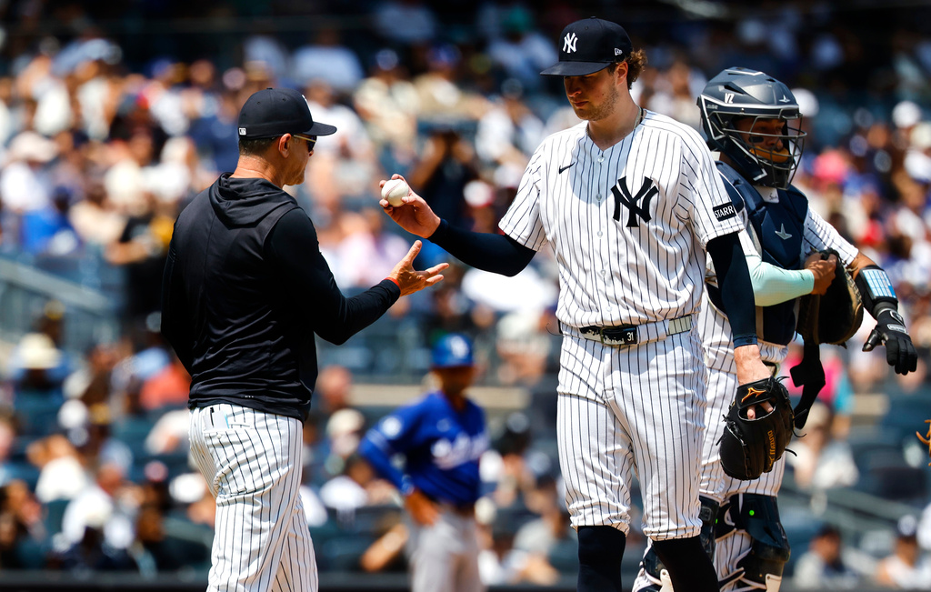 New York Yankees manager Aaron Boone, left, takes the ball from pitcher Cam Schlittler, second from left, during the fifth inning of the first game of a baseball doubleheader against the Los Angeles Dodgers, Sunday, July 19, 2026, in New York. (AP Photo/Noah K. Murray)