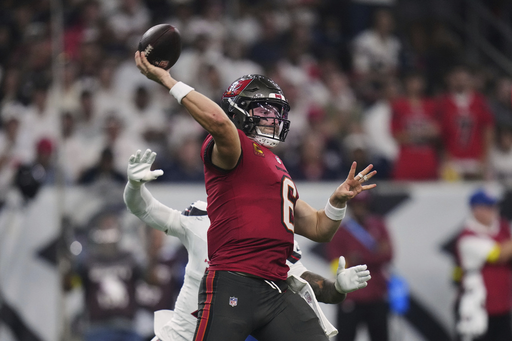 Tampa Bay Buccaneers quarterback Baker Mayfield (6) throws a pass under pressure from Houston Texans safety Jalen Pitre, rear, in the second half of an NFL football game Monday, Sept. 15, 2025, in Houston, Texas. (AP Photo/Eric Gay)