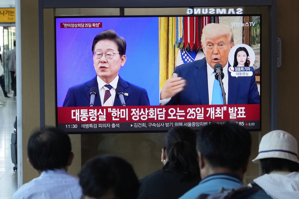 People watch a TV screen showing a file image of South Korean President Lee Jae Myung, left, and U.S. President Donald Trump during a news program at the Seoul Railway Station in Seoul, South Korea, Tuesday, Aug. 12, 2025. The signs read, "The presidential office announced that the South Korea-U.S. summit will be held on the 25th." (AP Photo/Ahn Young-joon)