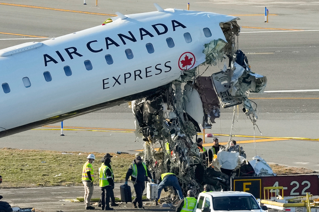 NTSB officials and aircraft maintenance workers pick through debris and remove luggage as they inspect the wreckage of an Air Canada Express jet, Tuesday, March 24, 2026, just off the runway where it had collided with a Port Authority fire truck Sunday night at LaGuardia Airport in New York. (AP Photo/Yuki Iwamura)