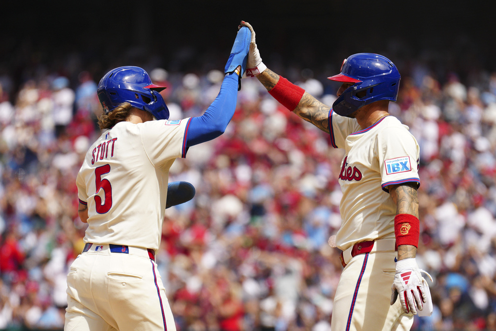 Philadelphia Phillies' Bryson Stott (5) and Nick Castellanos high five after scoring on an RBI double hit by Rafael Marchán off Washington Nationals pitcher Jake Irvin during the second inning of a baseball game, Sunday, Aug. 24, 2025, in Philadelphia. (AP Photo/Derik Hamilton)