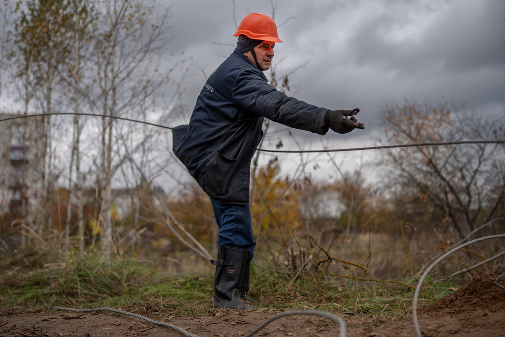 Wearing worn down gloves and uniform, a worker repairs power lines damaged by a Russian attack, Thursday, Oct. 16, 2025, in Shostka, Ukraine. (AP Photo/Julia Demaree Nikhinson)